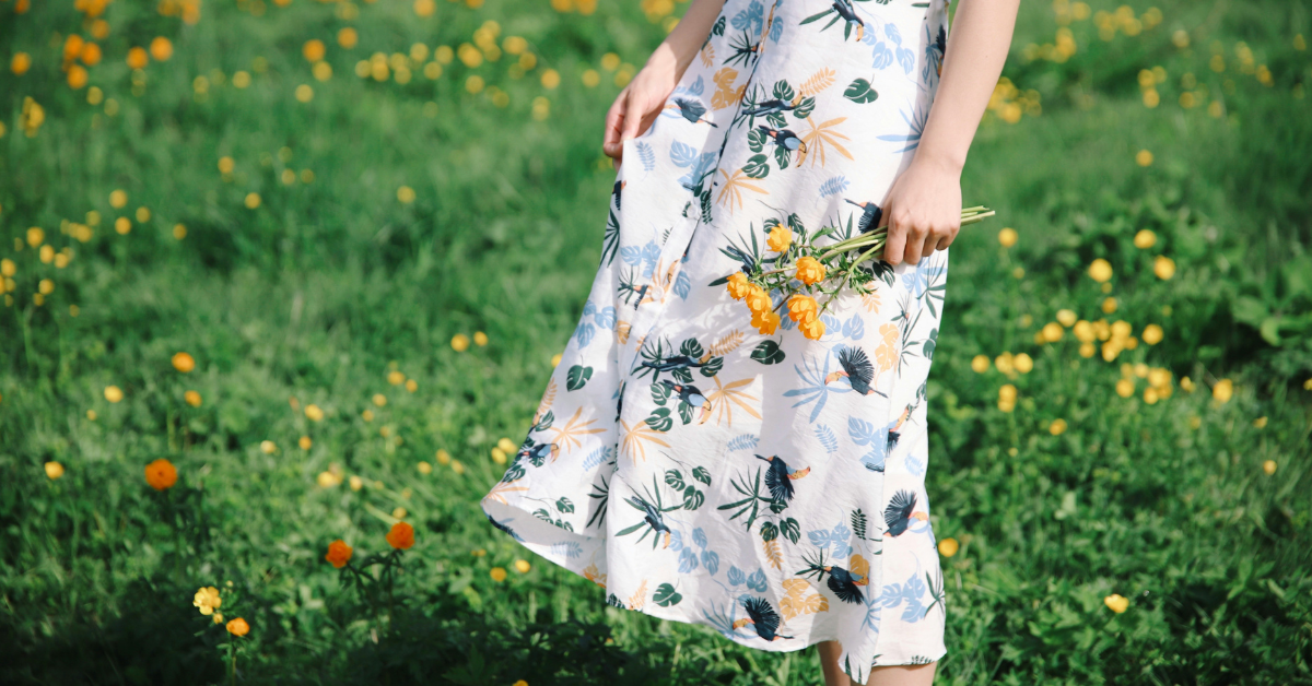Mujer con vestido veraniego y flores en la mano