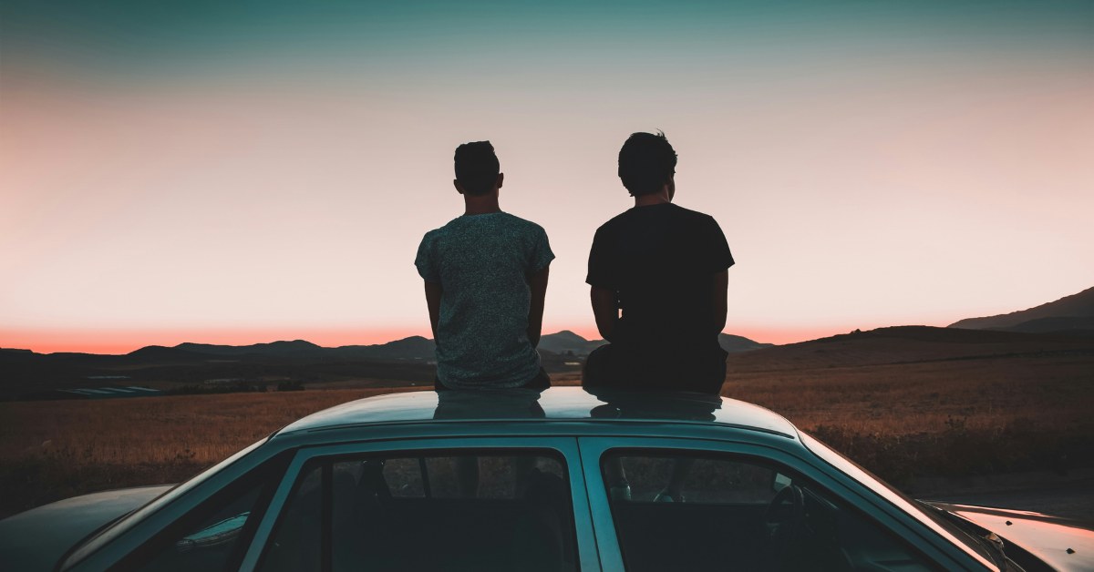 Personas jóvenes viendo atardecer desde el techo del coche
