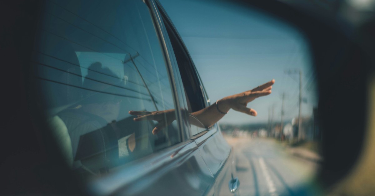 Persona sacando mano por la ventanilla del coche